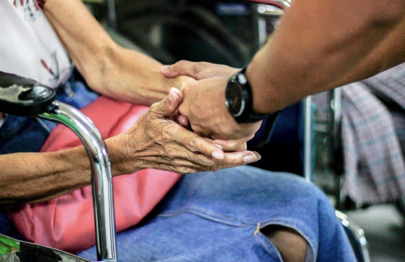 Close-up of two people holding hands, symbolizing support and care.