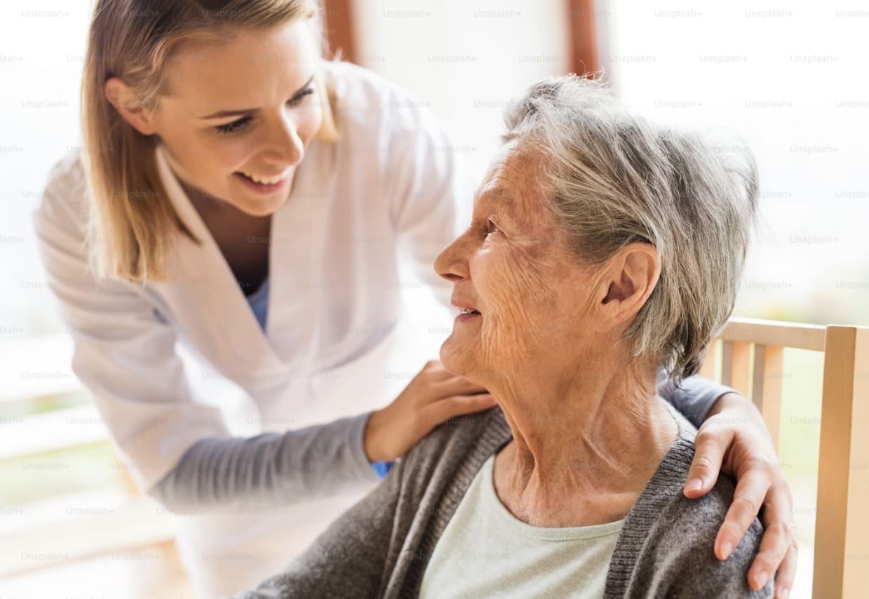 A caregiver warmly interacts with an elderly woman, sharing a joyful moment.
